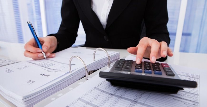Profissional calcula contribuições previdenciárias em documentos contábeis.